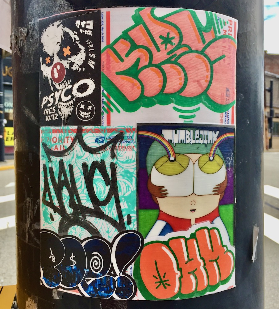 colorful collage of cartoon images, stickers, advertiments attached to utility pole