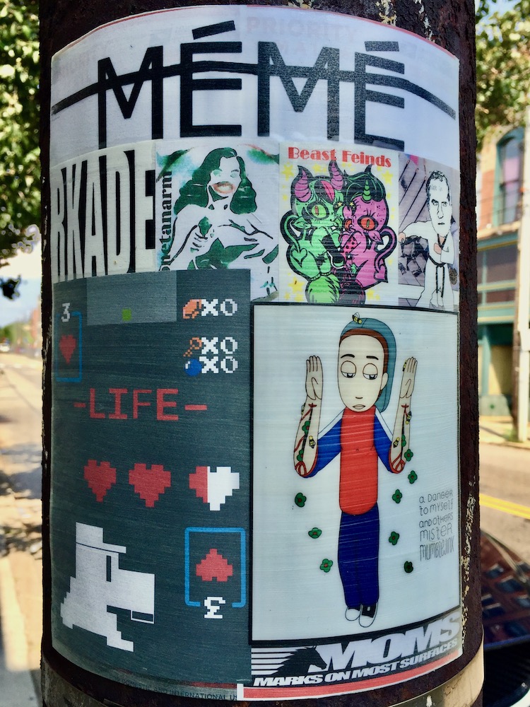 colorful collage of cartoon images, stickers, advertiments attached to utility pole