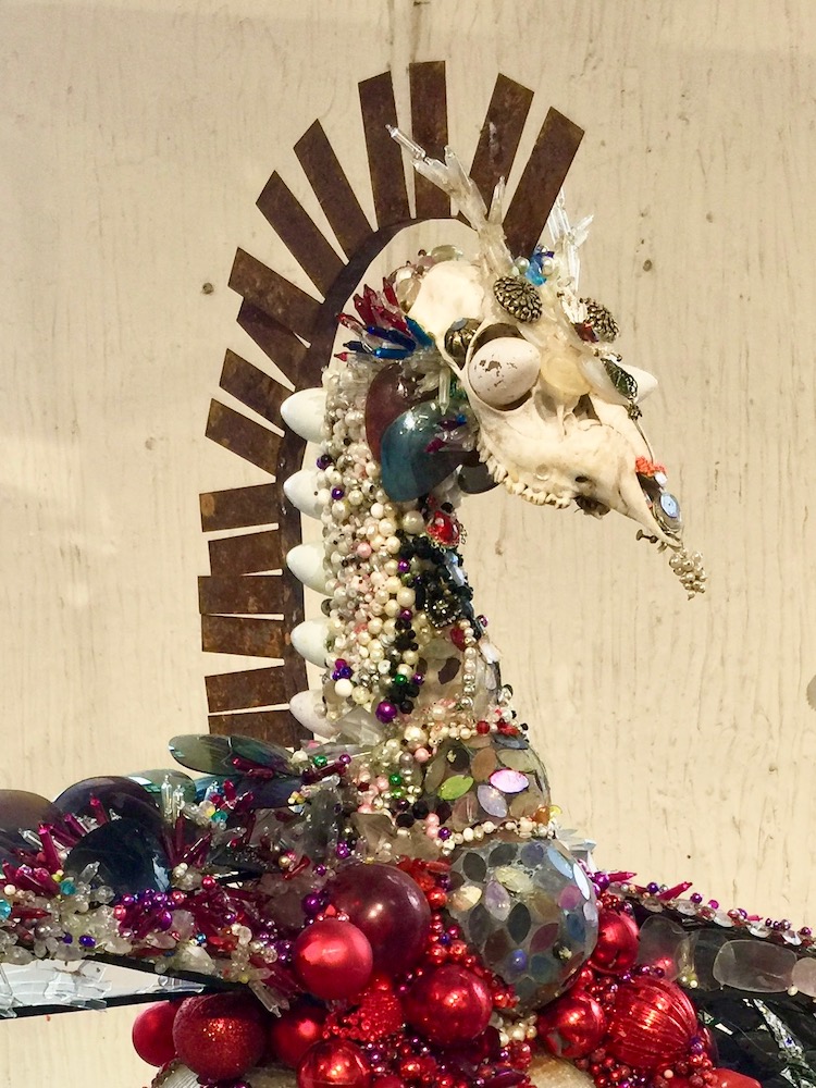 assemblage artwork by Glendon Hyde made with recycled animal skull, plastic beads, sunglasses, and Christmas ornaments
