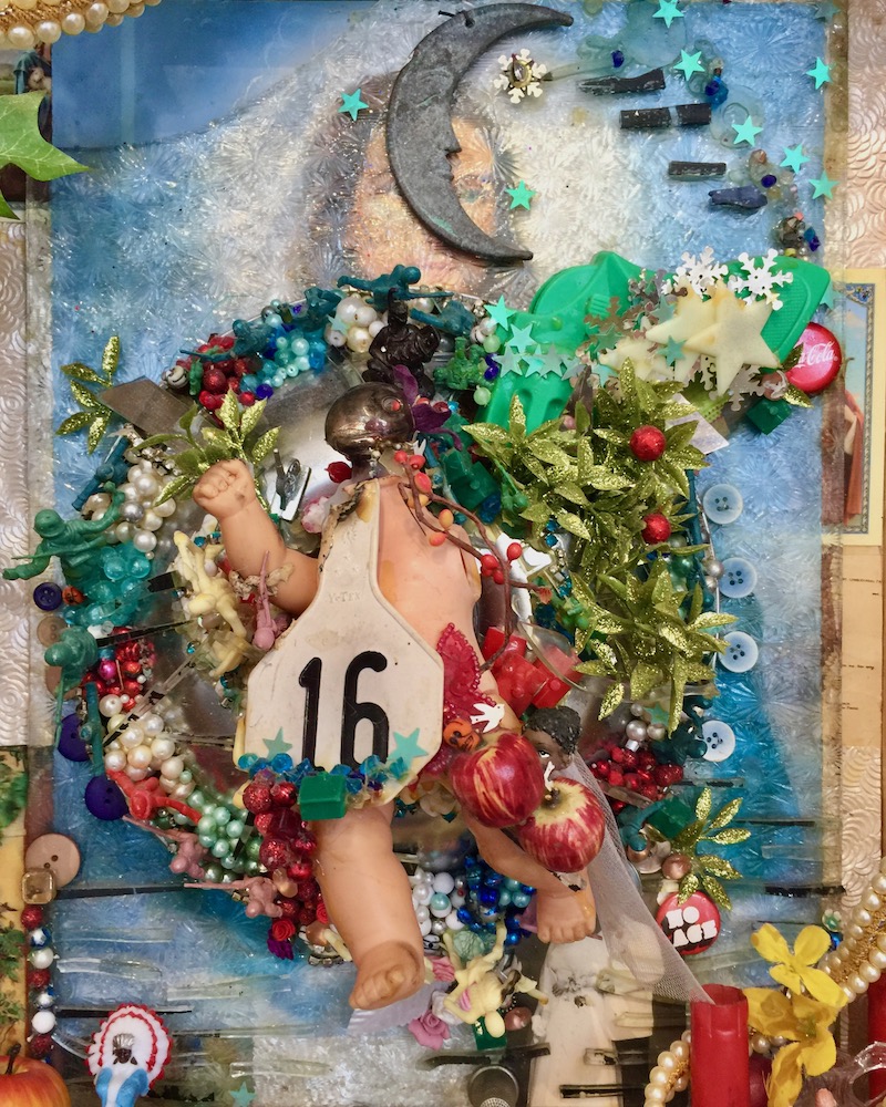 assemblage artwork by Glendon Hyde including baby doll, beaded wreath, false flowers, and image of woman behind glass