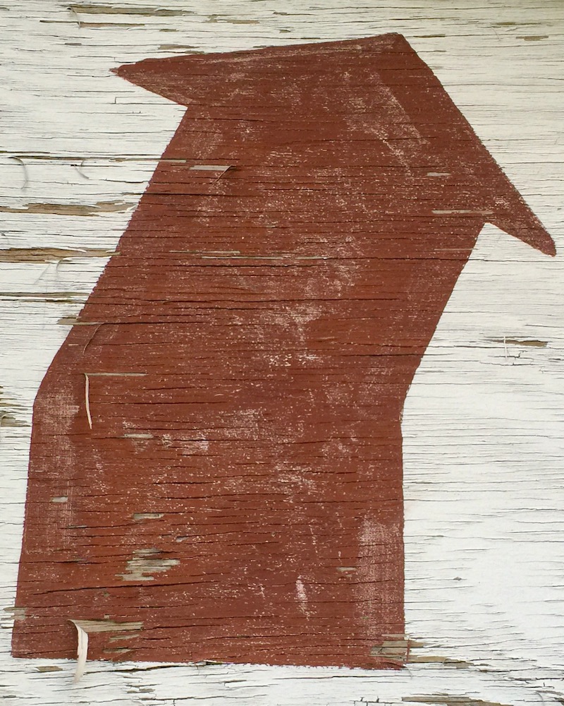 wide arrow painted on wooden board