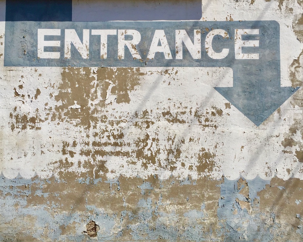 old masonry wall with blue arrow with the word "Entrance"