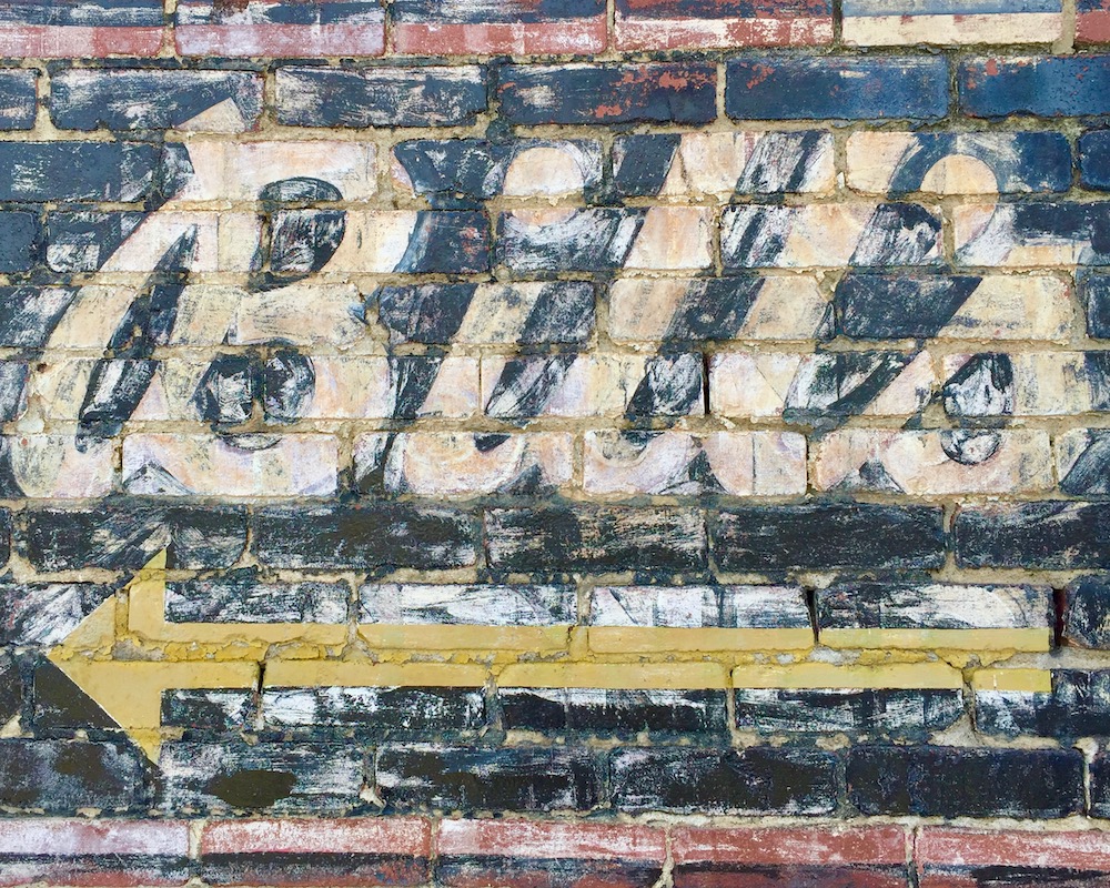 ghost sign for Bill's bar painted on brick wall