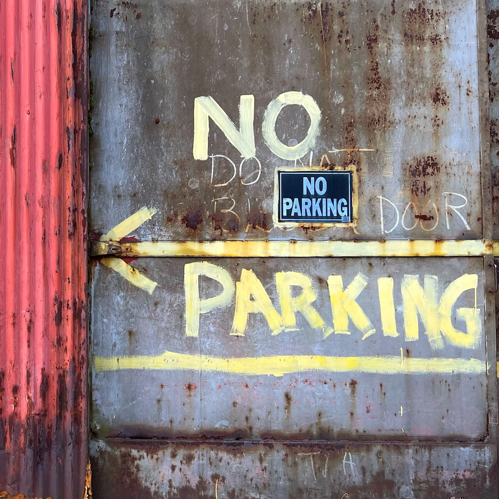 steel door painted with "no parking" and arrow