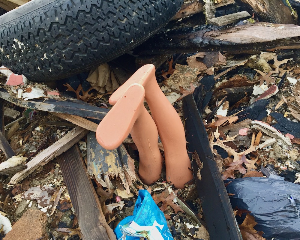doll's legs sticking out of debris from demolished house