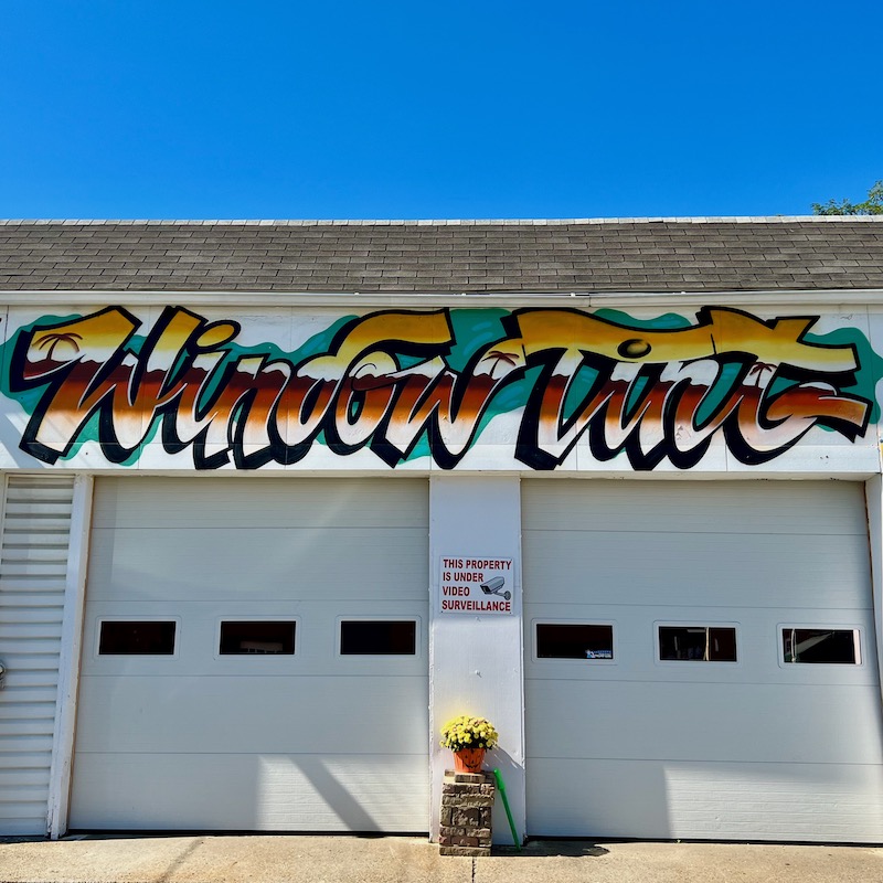 graffiti-style sign reading "Window Tint" on garage