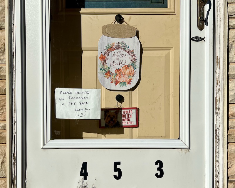 hand-written message with package-delivery instructions taped to front door of house