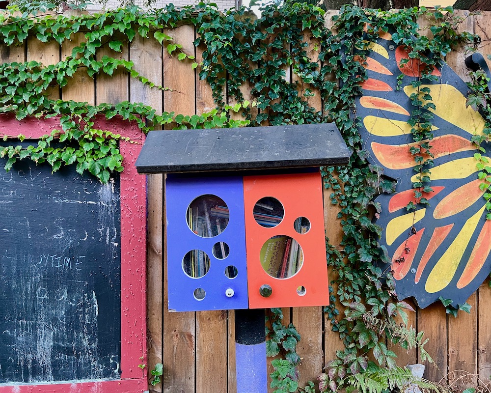 little free library painted blue and red with large circular window holes