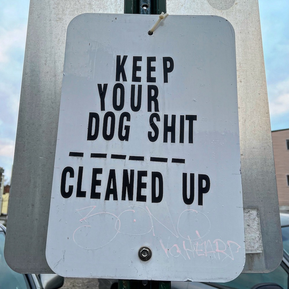 message to keep dog poop cleaned-up on parking sign
