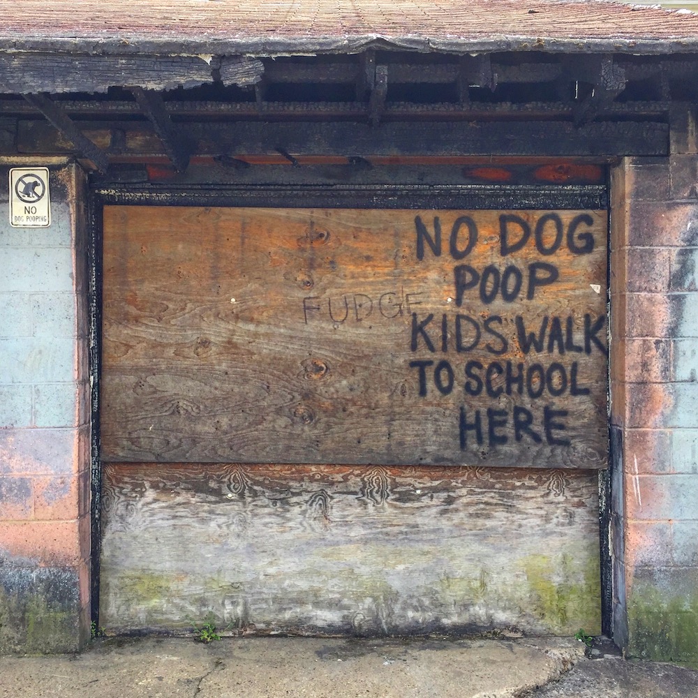 no dog poop message spray painted on wood covering garage door