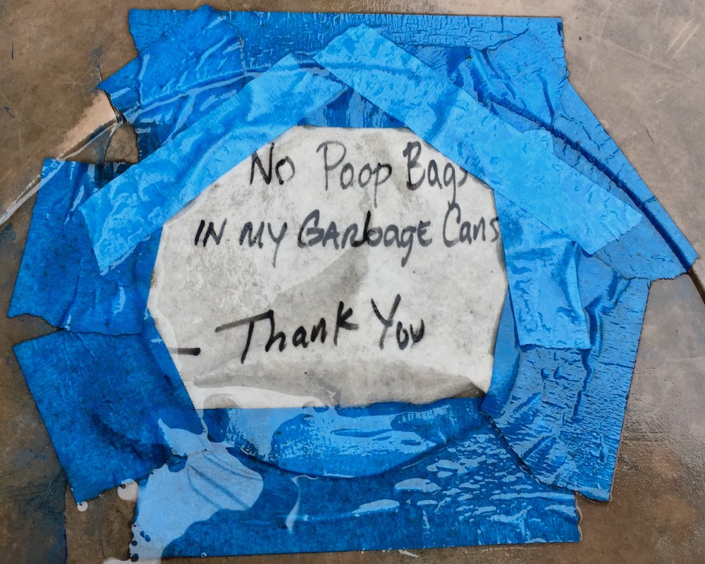 message taped to garbage can saying "no poop bags"