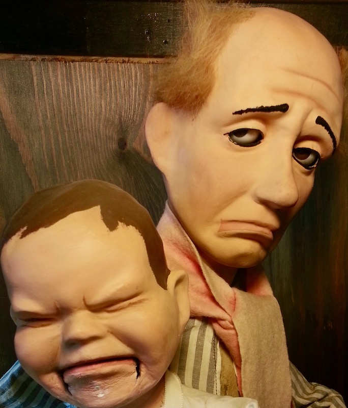 two ventriloquist dummies, both with sad facial expressions