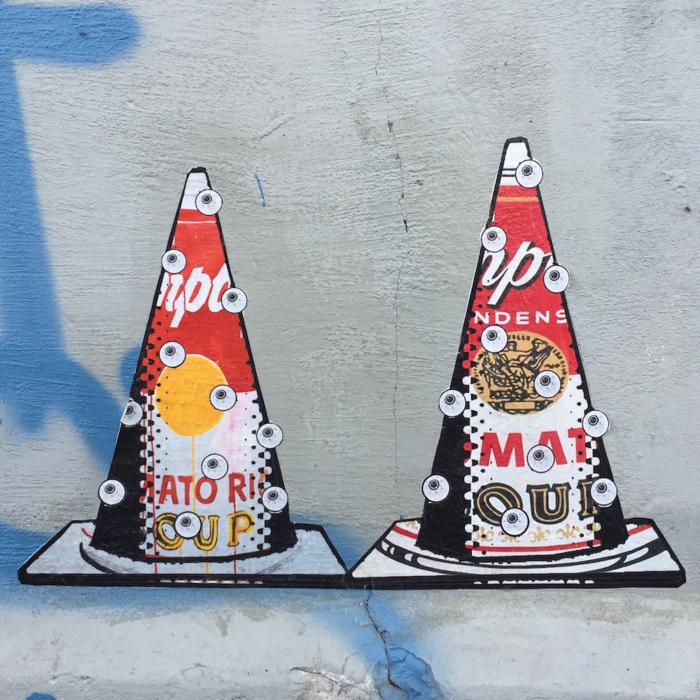 street art of traffic cones with Campbell's Soup background and floating eyeballs