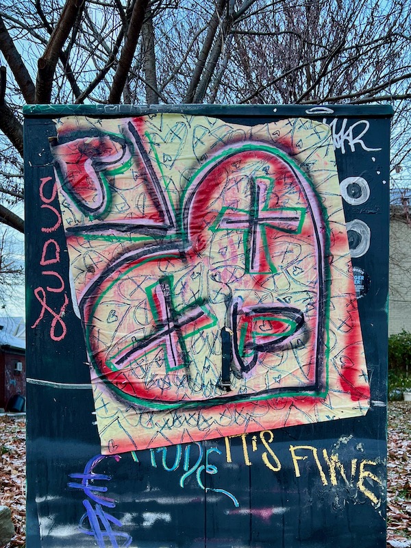 wheatpaste street art of heart-shaped face with Xs over eyes