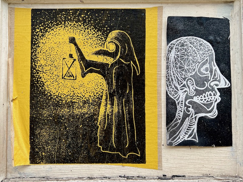 colorful collage of printed paper images layered on plywood covering vacant storefront