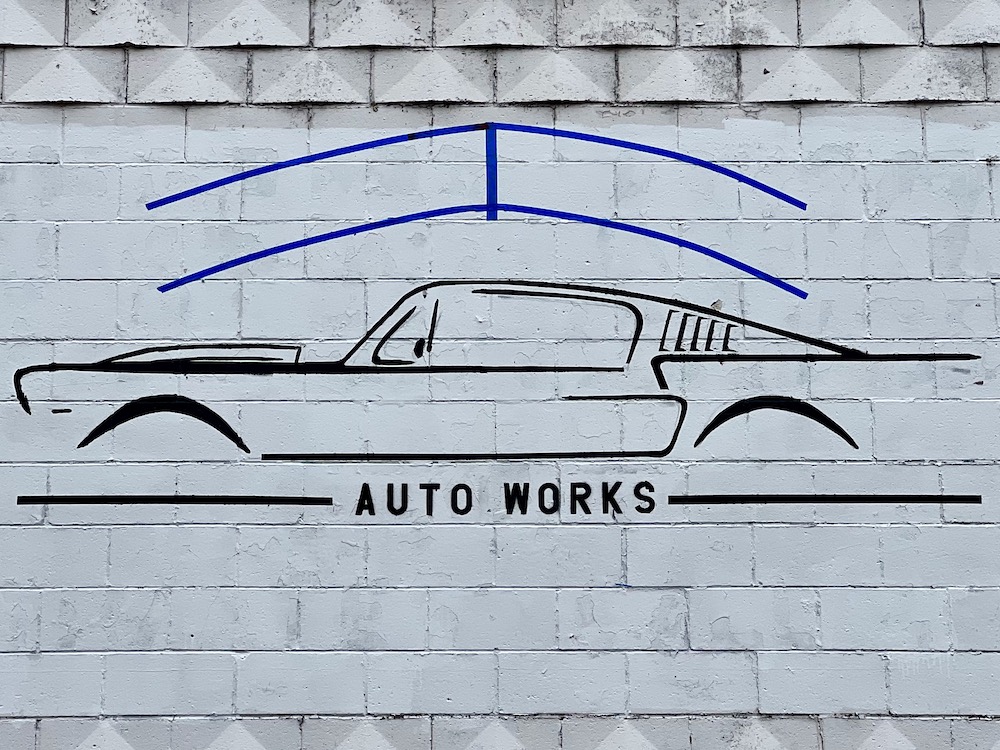 mural on cinderblock wall of 1960s Ford Mustang for Auto Works repair shop
