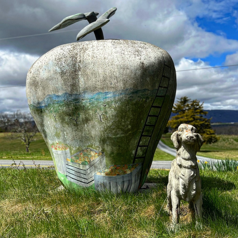 large statue of painted apple and smaller dog statue