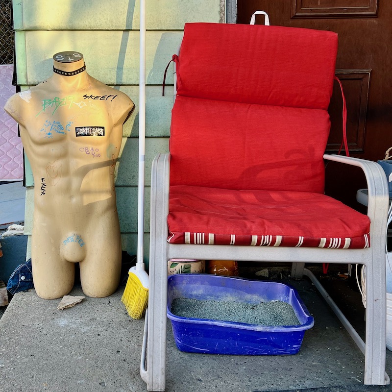 mannequin torso and cat box on porch of house