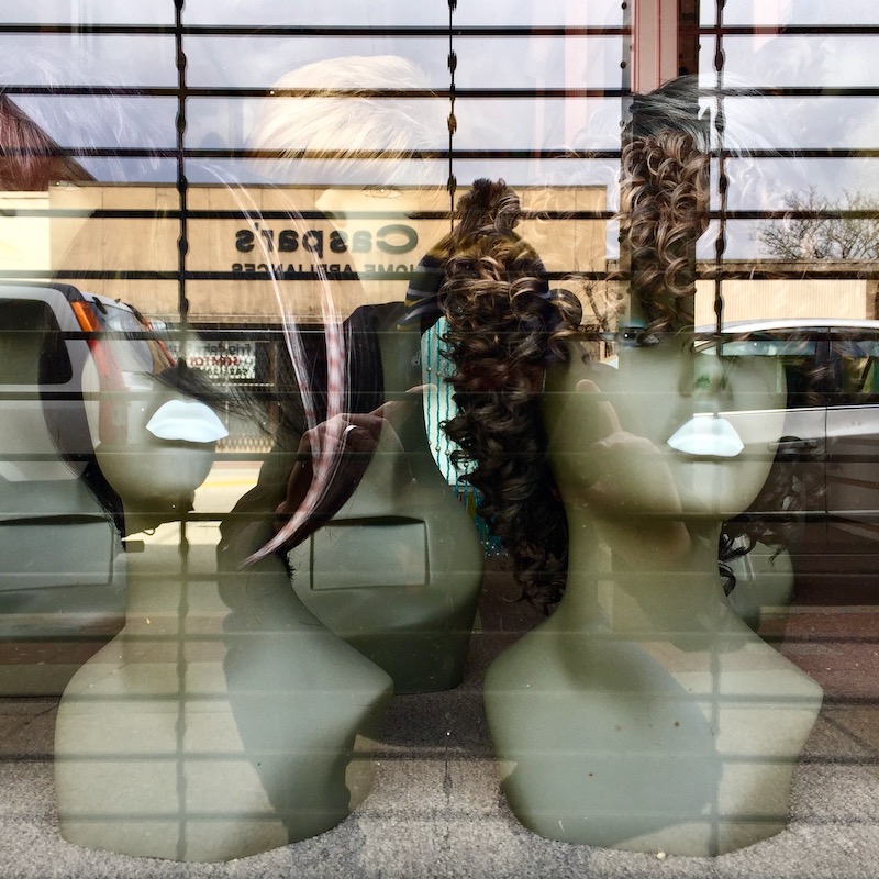pair of mannequin heads with wigs and white lipstick