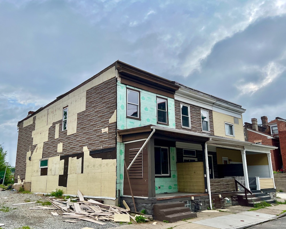 set of three row houses in mid-renovation showing many layers of different siding types