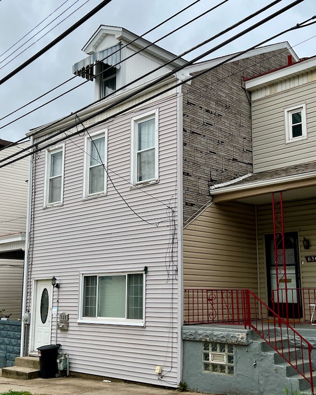 pair of row houses where wall siding of one matches porch siding of the other