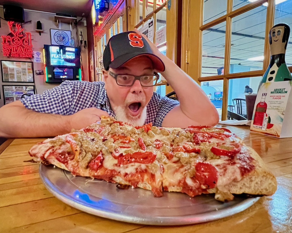man with excited expression looking at large pizza