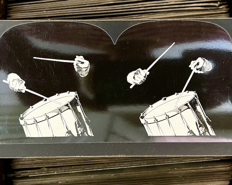stereoscope view card of snare drum and drummer's hands and sticks