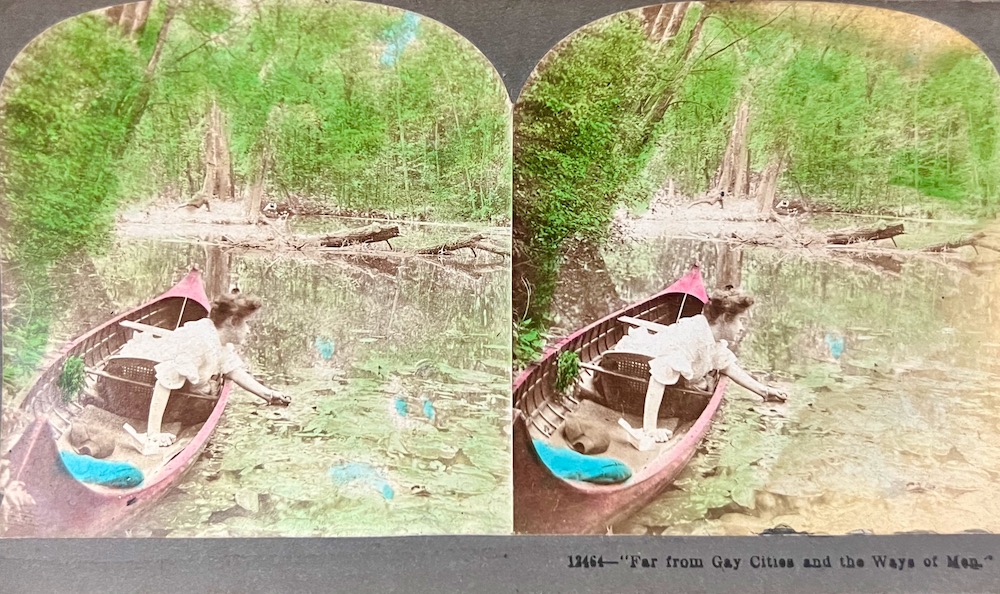 hand-tinted stereoscope view card of woman in canoe in river
