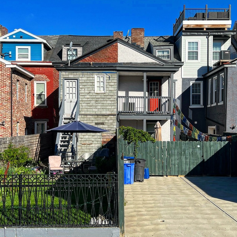 side-by-side row houses, seen from the rear, with very different backyards