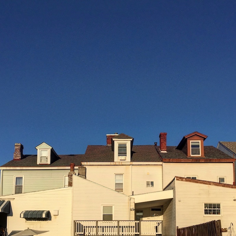 three similar-looking row houses with white siding, seen from the back