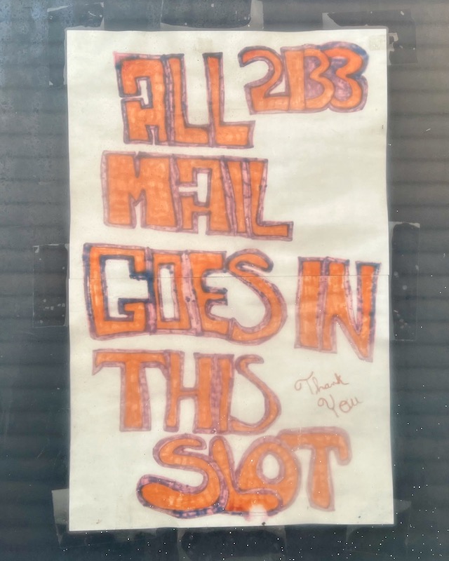 handmade sign on front door window directing mail delivery to mail slot