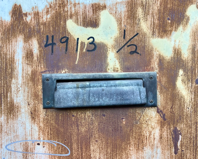 steel door with handwritten address above mail slot