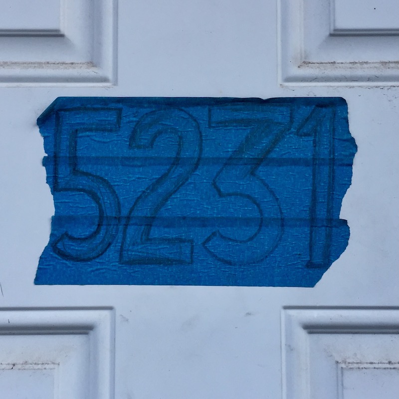 home address drawn on blue painter's tape attached to front door