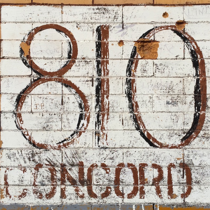 hand-painted address marker on brick wall