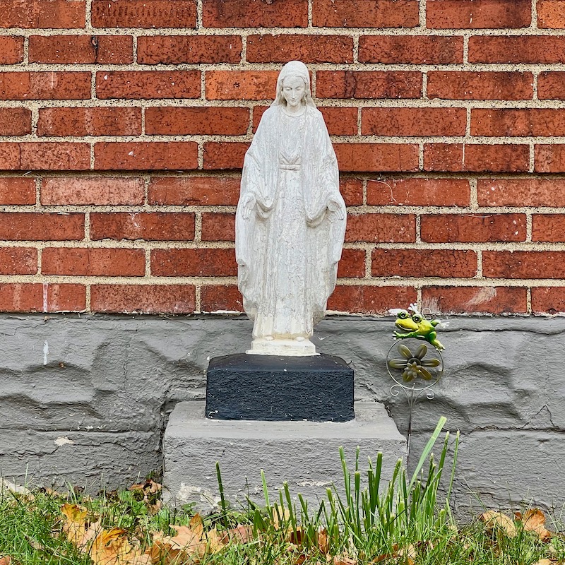 statue of Mary in front of older house