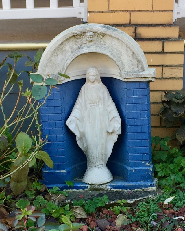 statue of Mary in front of older house