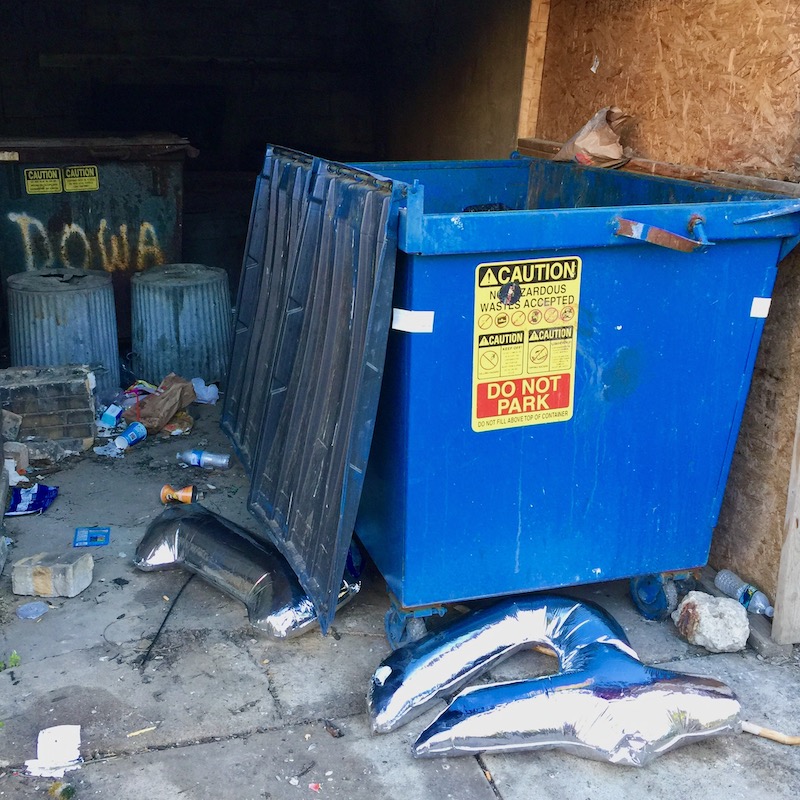 "1" and "4"-shaped balloons outside of a small dumpster in a garage