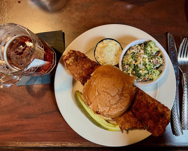 plate with large fish sandwich and broccoli salad