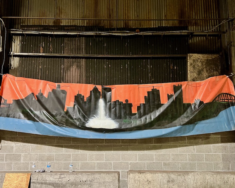 painting of downtown Pittsburgh skyline hung on sagging canvas in warehouse