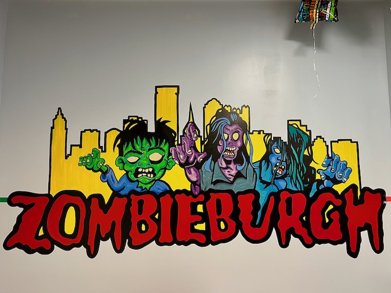mural in arcade including downtown Pittsburgh skyline with cartoon zombies