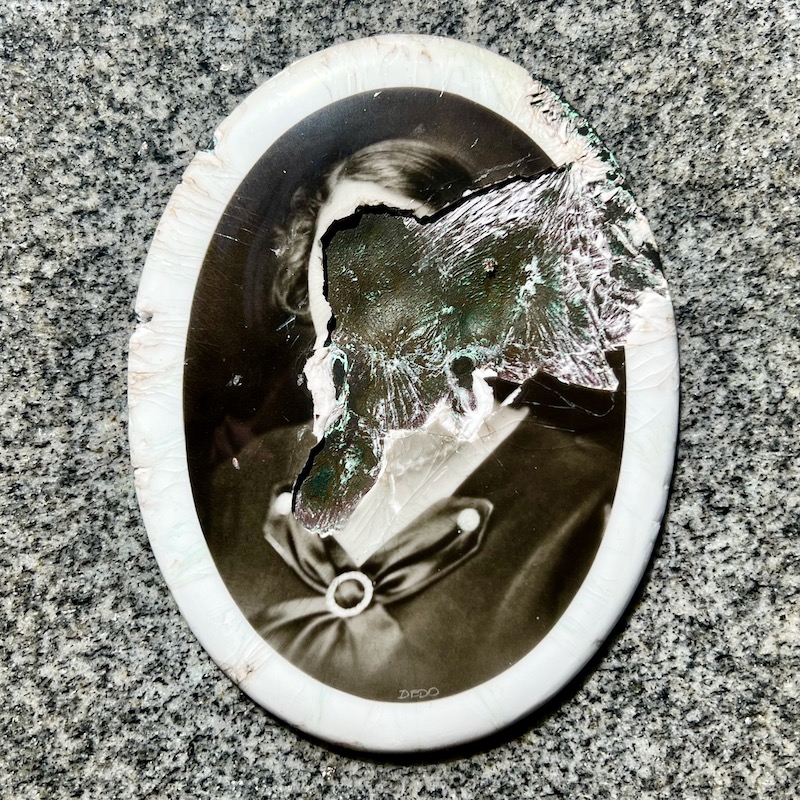 defaced ceramic photograph inset in gravestone
