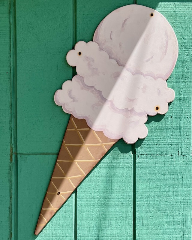 ice cream shop signage with large cone in sun and shade