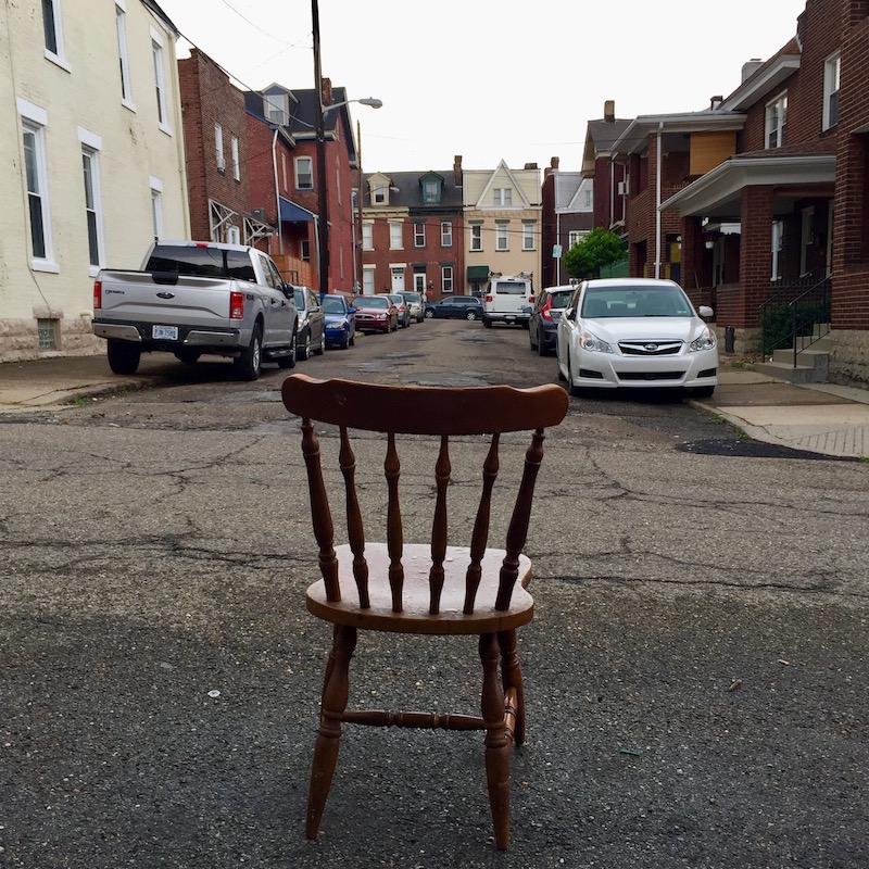 wooden chair holding parking spot on street
