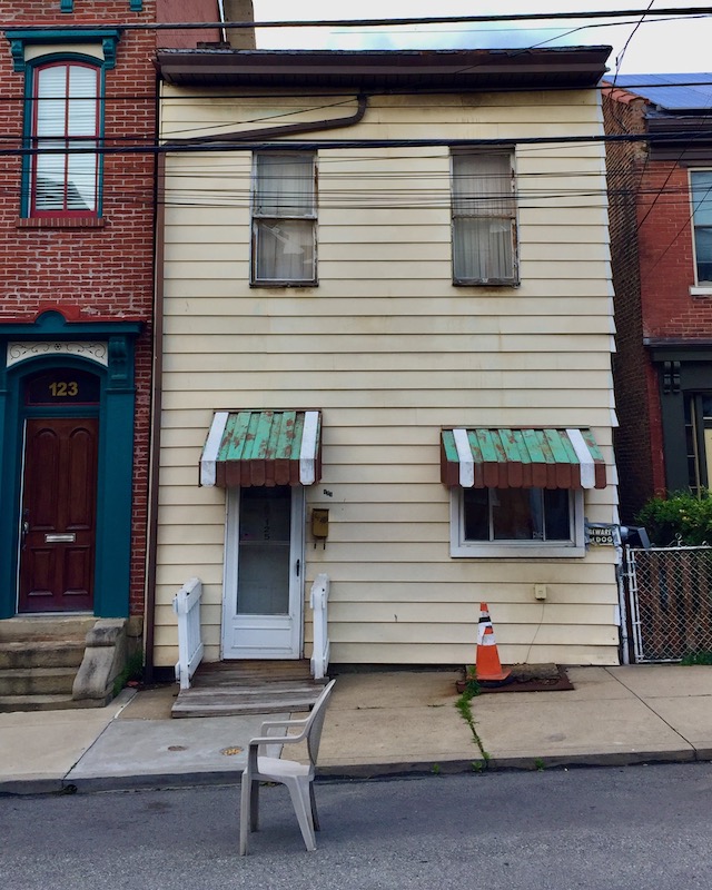 plastic lawn chair holding parking spot in front of small house