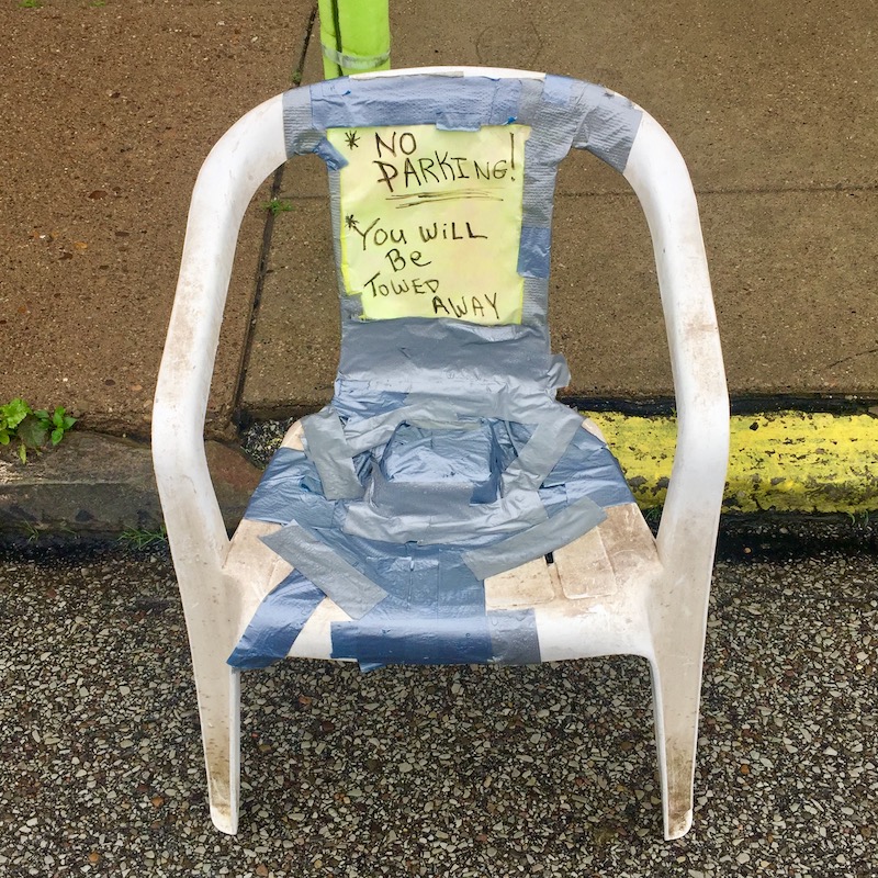 plastic lawn chair with "No parking" message