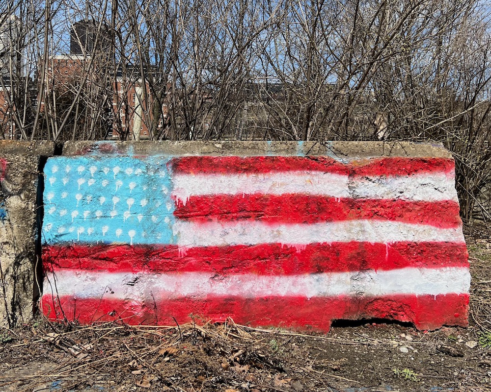 American flag spray-painted on cement barrier
