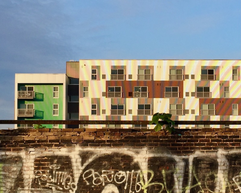 large new condo building behind old brick wall