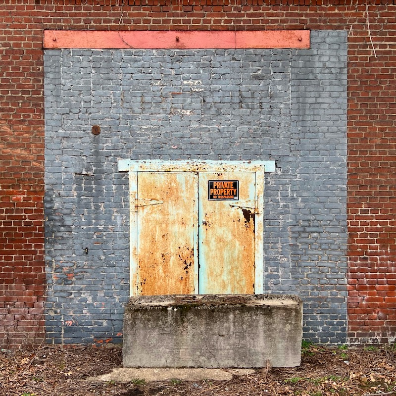 brick wall with doors blockaded by large cement piece