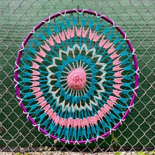 crochet art created on hula hoop and attached to chain link fence
