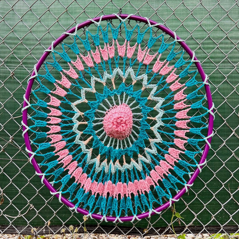 crochet art created on hula hoop and attached to chain link fence